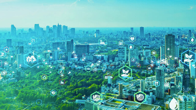 この画像は、近代的な都市の風景と、持続可能性、環境、テクノロジーに関連するアイコンが重ね合わされたものです。